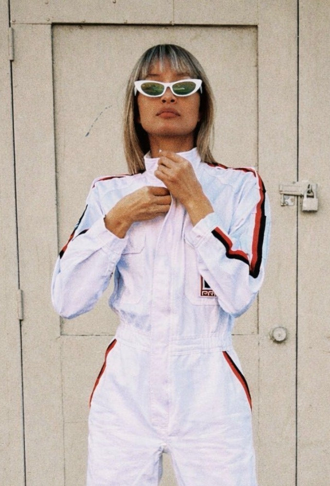 Person wearing a white tracksuit with red accents in front of a beige door.