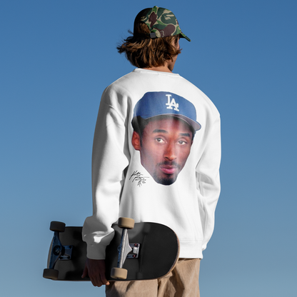 Person wearing a sweatshirt with a graphic design, holding a skateboard against a clear blue sky.