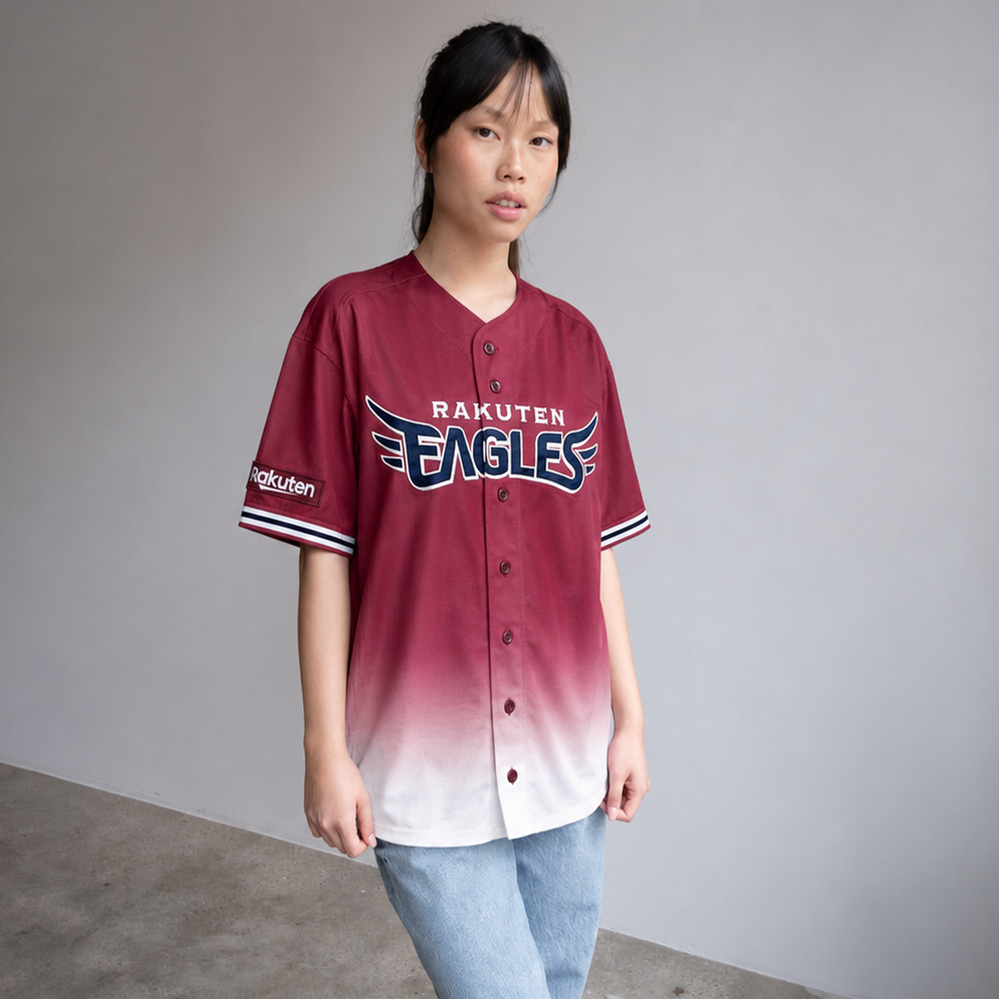 Person wearing a maroon and white baseball jersey with 'Rakuten Eagles' logo on a plain background