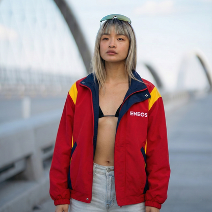 Person wearing a red jacket with ENEOS branding on a blurred background