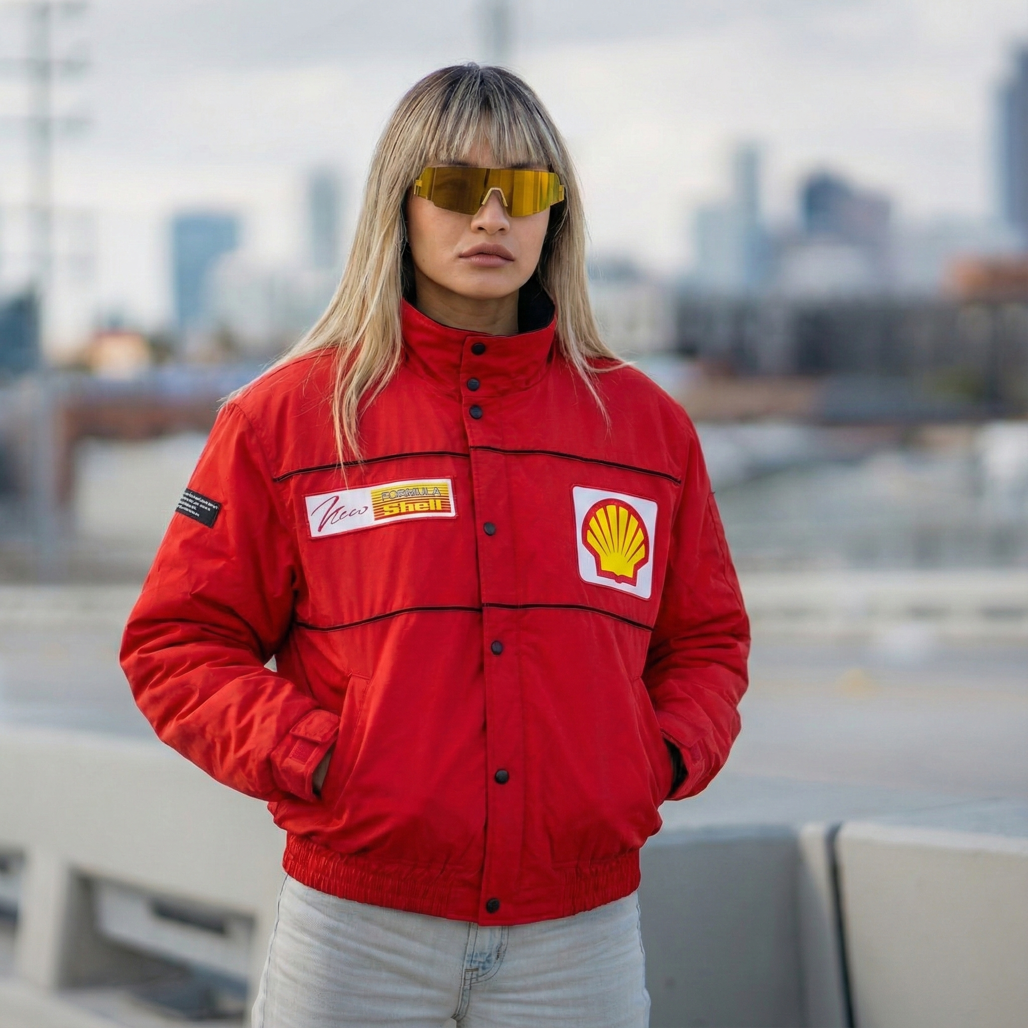 Person wearing a red racing jacket with visible logos against an urban background